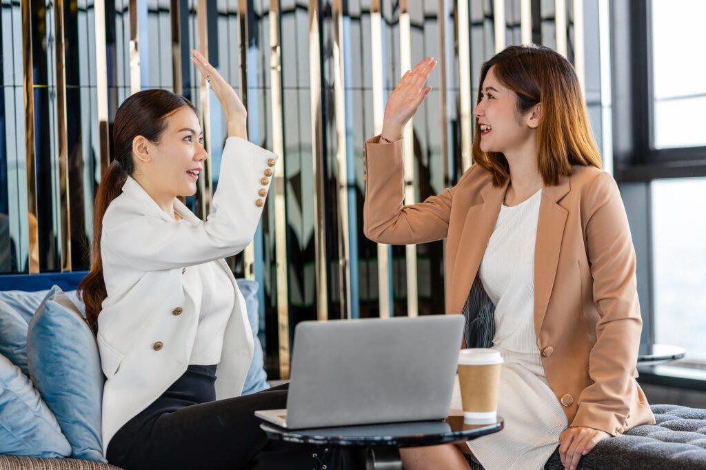 Two asian businesswomen hapiness celebrating together when checking success goal