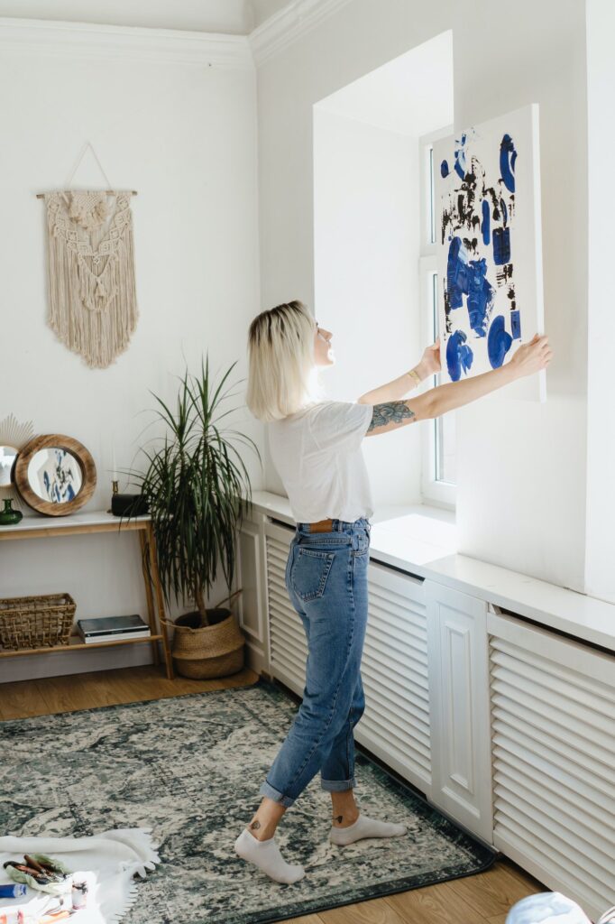 Young woman placing abstract paint on the wall