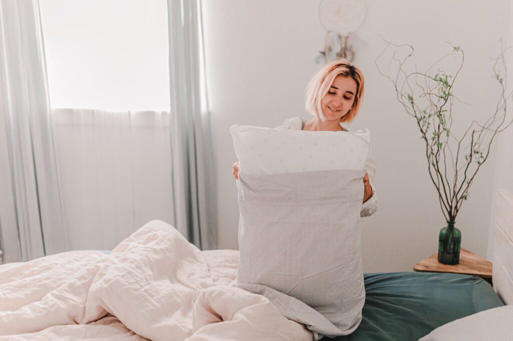 Blonde woman is cleaning at home. Spring cleaning and organizing. Changing the pillow cover.