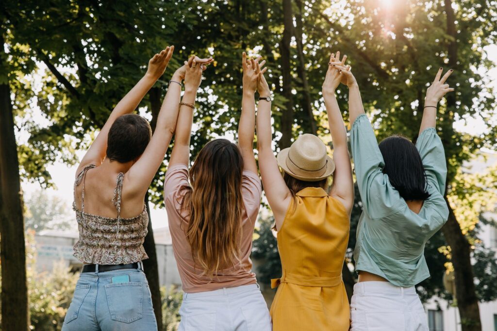 Group of four women together holding hands up in the air. Concept of women united.