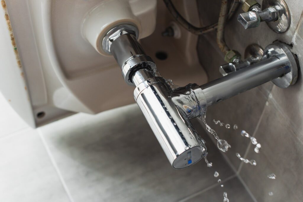 Leaking steel pipe under sink with water drops