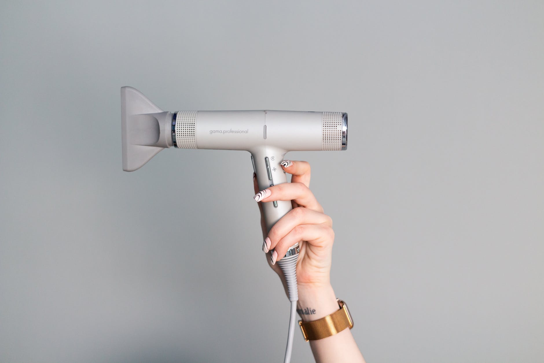 close up shot of a person holding a blow dryer, using hot tools too often is a hair mistakes