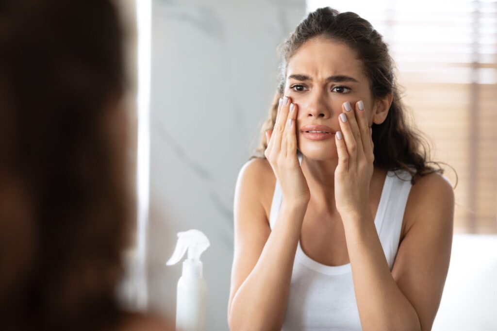 Unhappy Woman Looking At Wrinkles Touching Face Skin In Bathroom