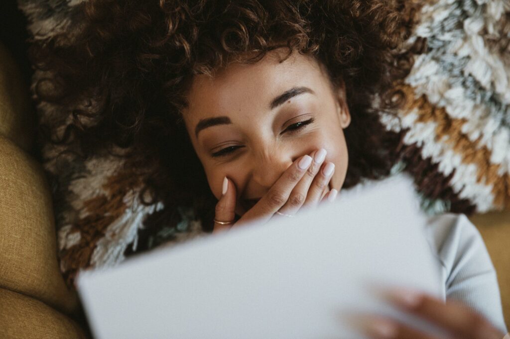 Woman lying and reading a letter on a couch