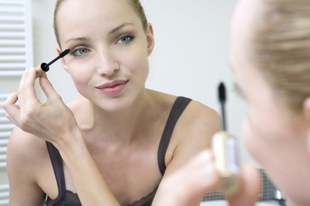 Young woman applying mascara, portrait, close-up